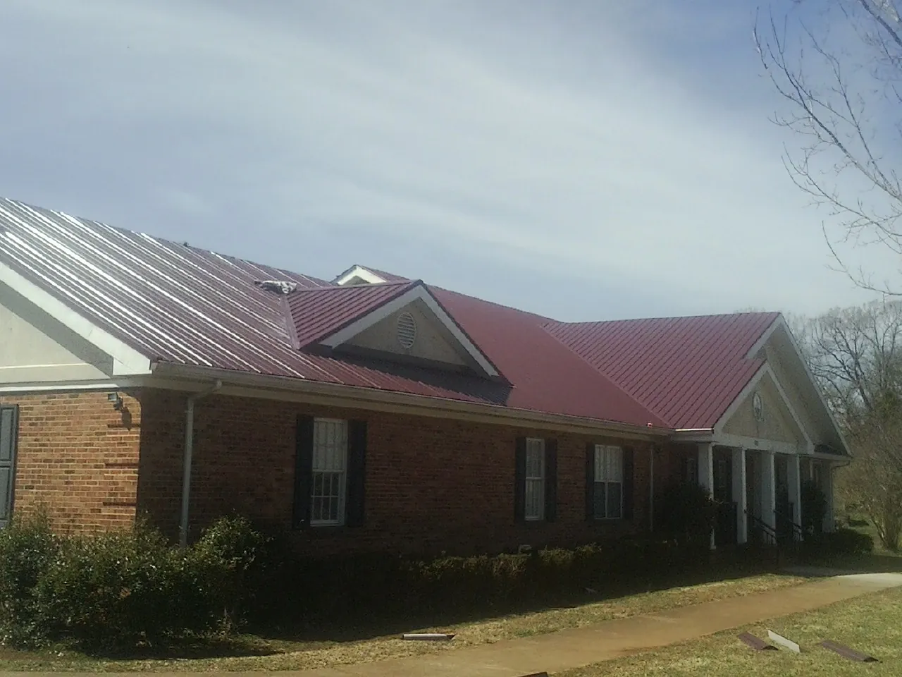 Red metal roof with gabled entries on a long brick building in Kirkwood